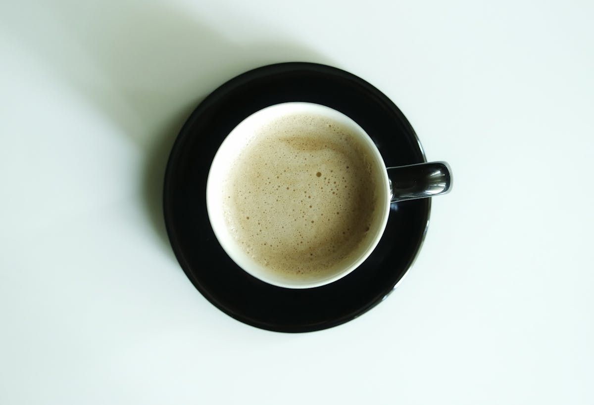An overhead flat white with latte art in a ceramic cup.